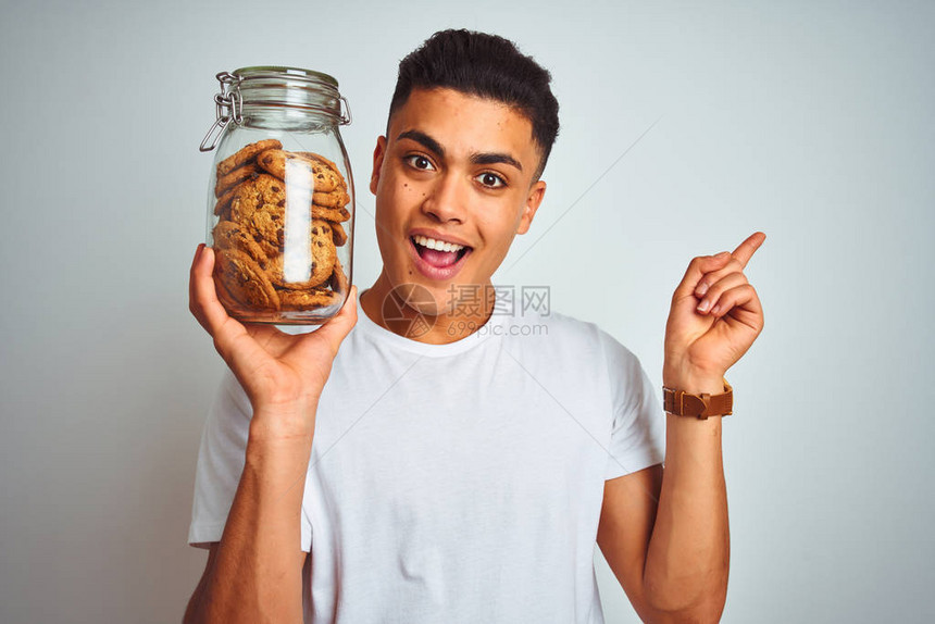 年轻的巴西男子拿着一罐饼干站在孤立的白色背景上图片