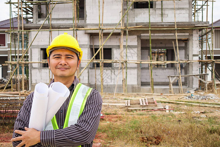 戴防护头盔的亚洲商人建筑工程师和房屋建筑工地图片