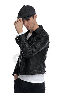 一个穿着黑色皮夹克和帽子的帅气休闲男士的侧视图图片