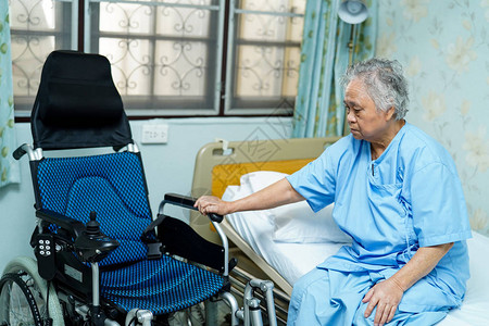 亚洲老年或老年妇人患者坐在护理医院病房电动轮椅床上图片