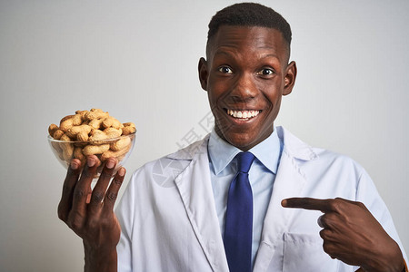 非洲裔美国医生拿着一碗花生在孤立的白色背景上图片