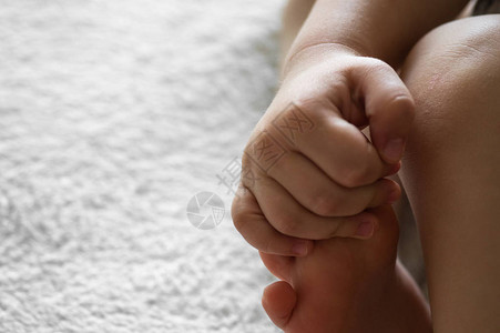 一个小孩将他或她的手臂放在羊毛白色背景上皮肤腿儿童的概念父母图片