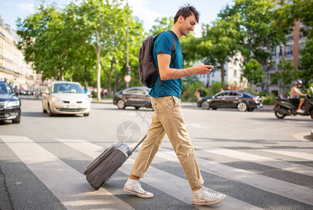 旅行男子用手机和手提袋在街上行走的图片