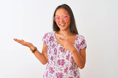 年轻的女人在孤立的白色背景上穿着花卉t恤和粉红色眼镜图片