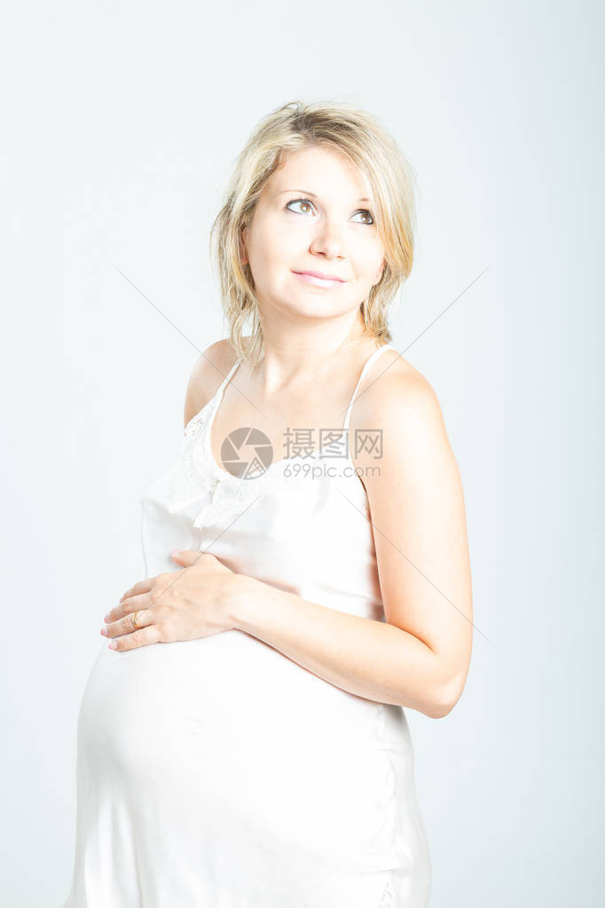 孕妇在白色睡衣触摸腹部的肖像图片