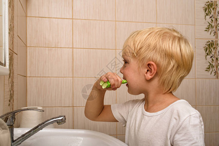 金发男孩勤劳地在浴室刷牙健康习惯图片
