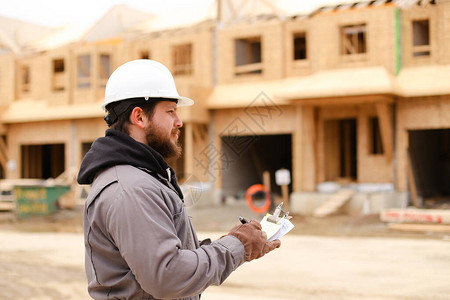 欧洲建造者在建筑工地的笔记本上绘制计划并戴上安全帽建筑专业和房图片