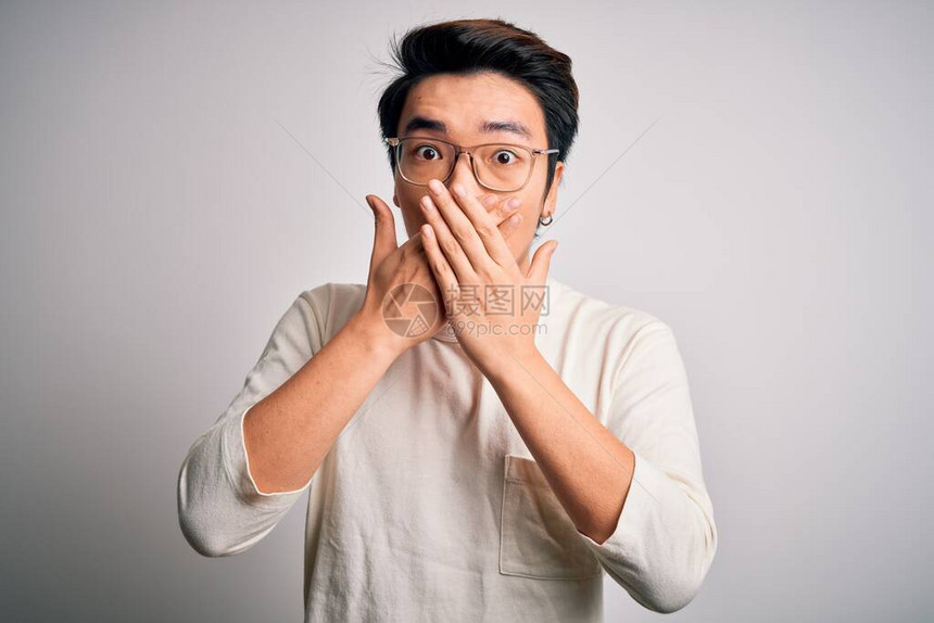 身穿轻便T恤和白底眼镜的英俊男青年因犯错而用双手遮住嘴部震图片