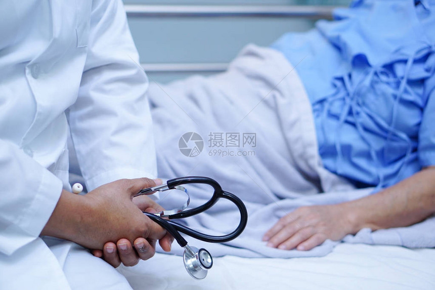 用听诊器检查病人的医生躺在医院病房的床上图片