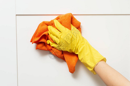 女在保护手套清洁厨房柜子中图片