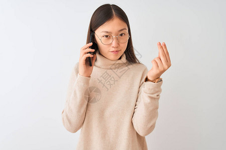 年轻女人在孤立的白色背景下用智能手机说话图片