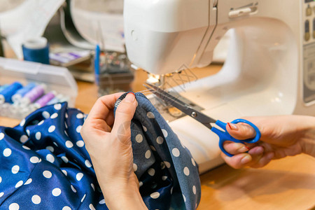 她用缝纫机缝完织布的边缘时缝衣师裁缝剪线只有她的图片