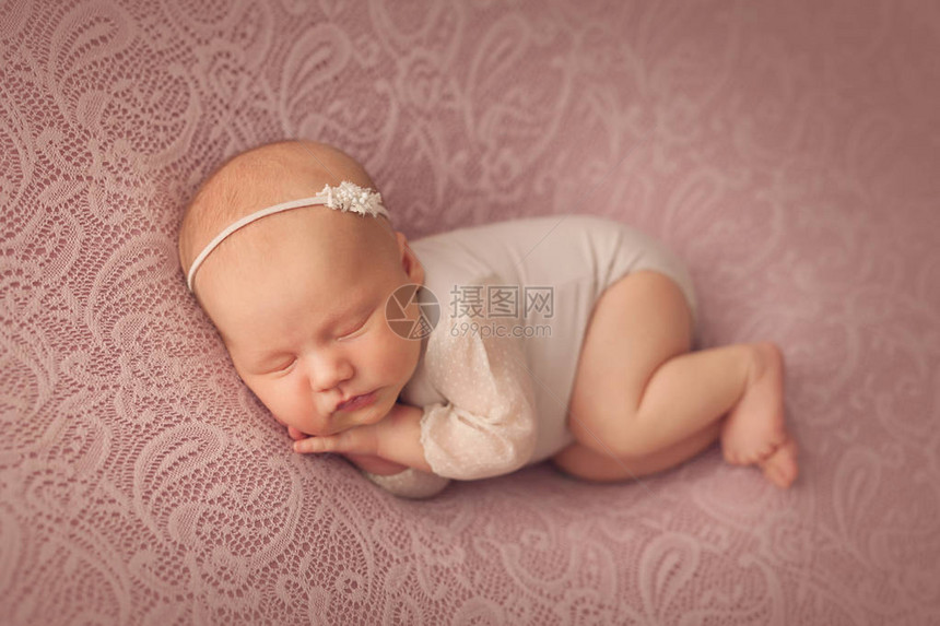 刚出生的婴儿睡在粉红色的背景上图片