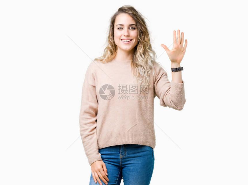 美丽的年轻金发女郎穿着毛衣在孤立的背景下显示并用五号手指向上方图片