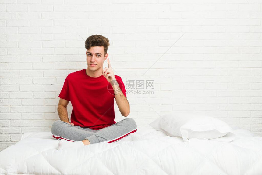 年轻的少年学生男人在床上展示一号图片