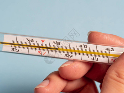 水银温度计在蓝色背景上孤立的女人手中使用温度计测量温度图片