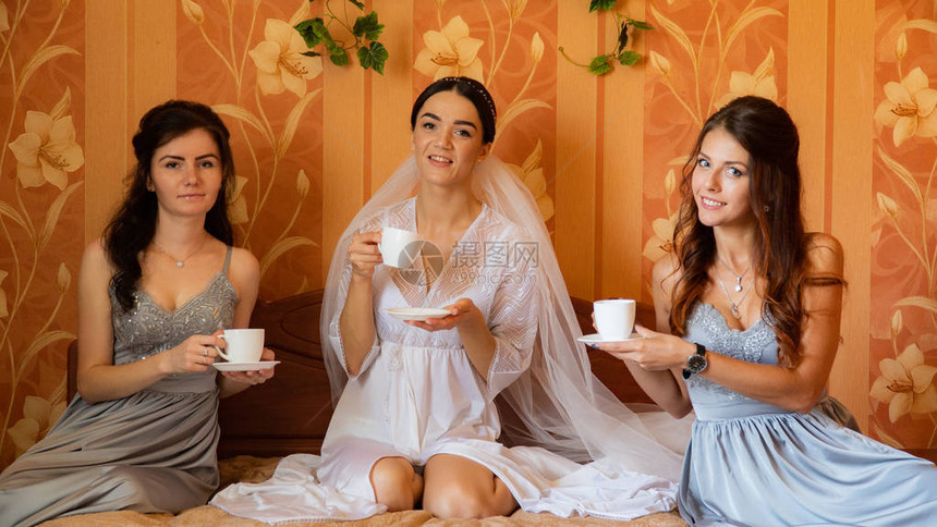 美丽的新娘女孩们早上在家的餐桌上玩得开图片