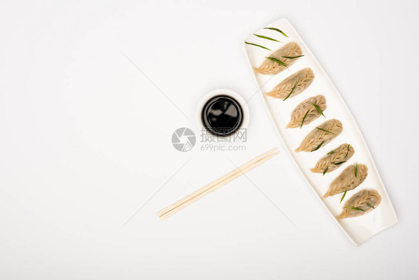 白色背景的筷子和酱油旁边盘子上美味的锅炉面图片