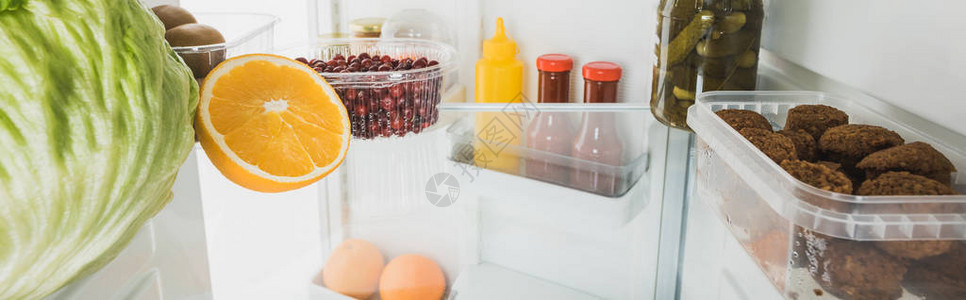 冰箱里有鲜果菜片和酱汁开着门白色图片