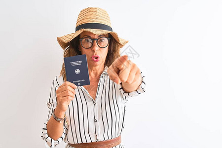 持有德国护照的高级旅游妇女在孤立的白色背景上用手指着相机和你图片
