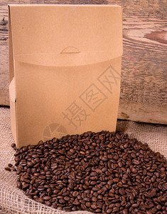 咖啡豆和木质背景上的牛皮纸袋侧视图图片