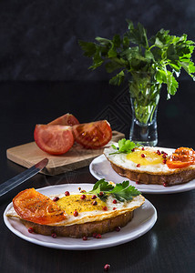 三明治和煎蛋番茄在盘子上在黑暗背图片