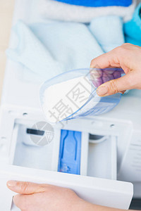 洗衣粉洗涤剂和测量杯子倒进机器中图片