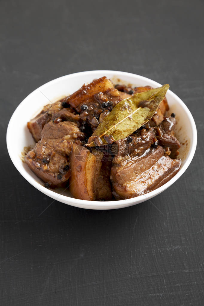 身着白色碗的菲律宾自制Adobo猪肉在黑色背景图片