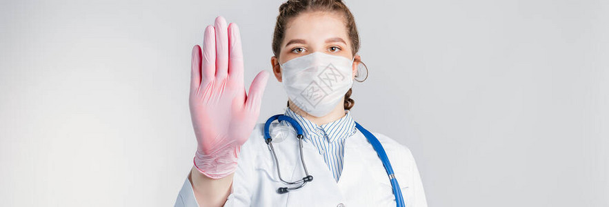 一位身着白大衣和粉色消毒手套的年轻美丽的女医生在白色背景上展图片
