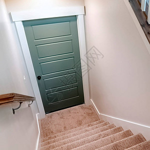 方形地毯的U形楼梯通向房屋的地下室门楼梯有棕色扶手高清图片