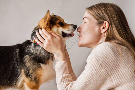 穿夹克的欧裔女人亲吻Corgipembroke狗图片