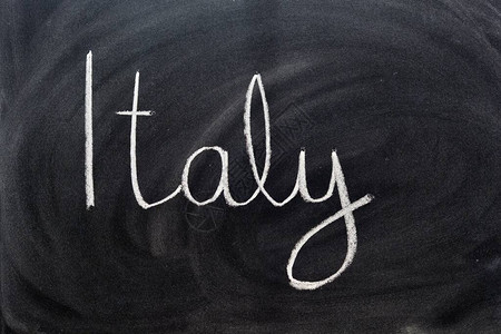 黑板上用粉笔手写的意大利这个词背景图片