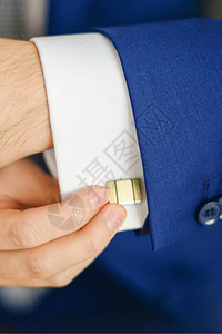 Groom或商人在穿蓝色西装的衬衫手图片