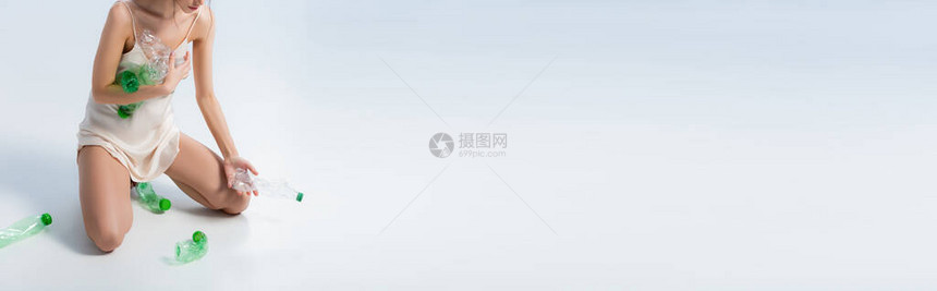 穿着丝绸衣服收集白色塑料瓶和生态概念的图片