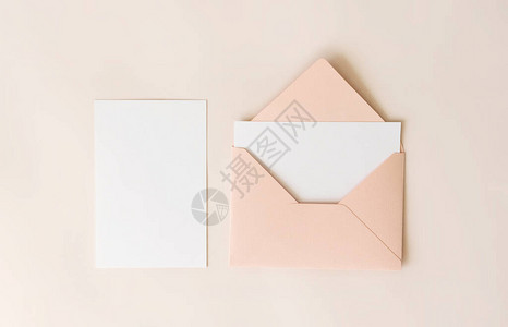 模拟粉红色信封内的空白字母和米色背景的白纸图片