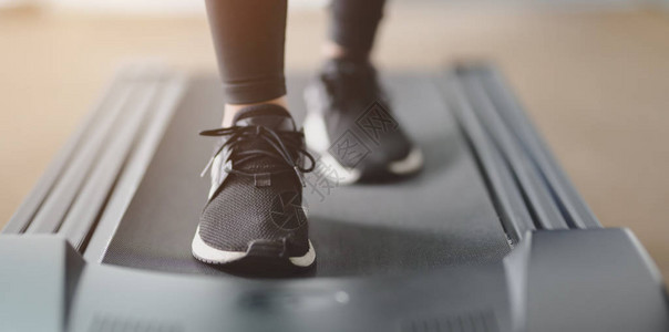 在健身房内的跑步机上穿着慢跑鞋跑步的女图片