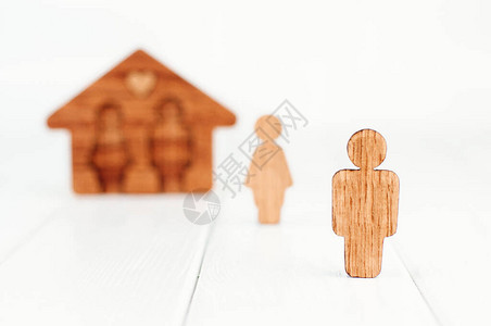 在女形象和房子前面的木制男形象在白色背景作为家庭关系问题的象征图片