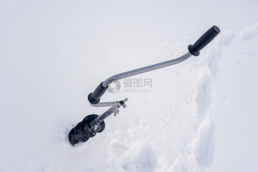 一次铁黑手持冰钻头有个弯曲的把手柄冬季在白雪背景下图片
