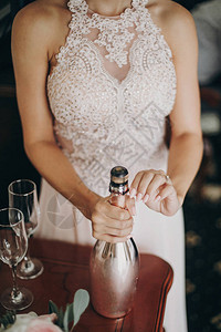 时髦的新娘或伴娘打开香槟瓶图片