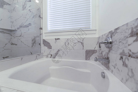 淋浴间和内置浴缸位于带黑白墙的浴室内闪发光的浴缸旁边有一扇带白色图片