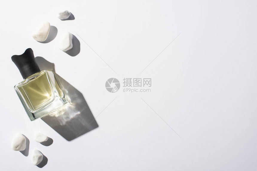 白色背景的石头附近的瓶子中家庭香图片