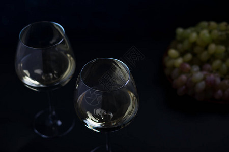 两杯白葡萄酒和两杯葡萄在背景图片
