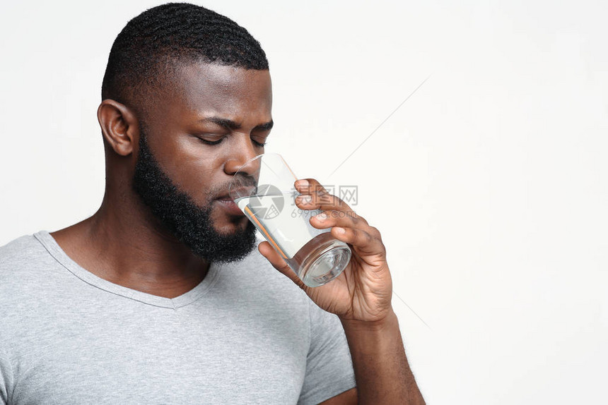 口渴的非洲年轻男子拿着一杯饮用水图片