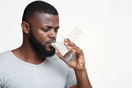 口渴的非洲年轻男子拿着一杯饮用水图片