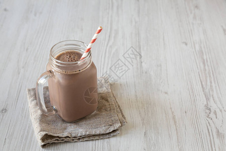 新英格兰自制巧克力奶昔装在玻璃杯加拉穆格上白色木质背景低角度视图片