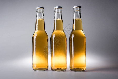 灰色背景中带啤酒的三个玻璃瓶背景图片
