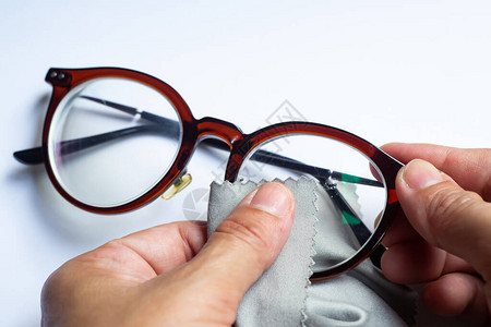 用微纤维清洁布清洁近视或近视眼镜的女手背景图片