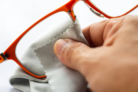 女右手用灰色微纤维清洁布清洁橙色近视或近视眼镜图片
