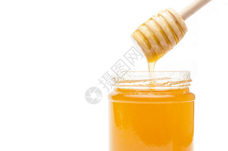 蜂蜜浸入一个装满白色背景蜂蜜的罐子里图片