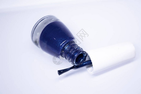 一瓶白色背景上溢出的蓝色指甲油指甲油指甲修指甲概念隔图片